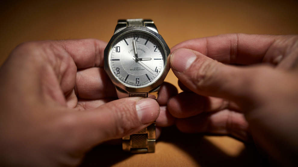 Un hombre cambia las manecillas de un reloj a las 3 horas