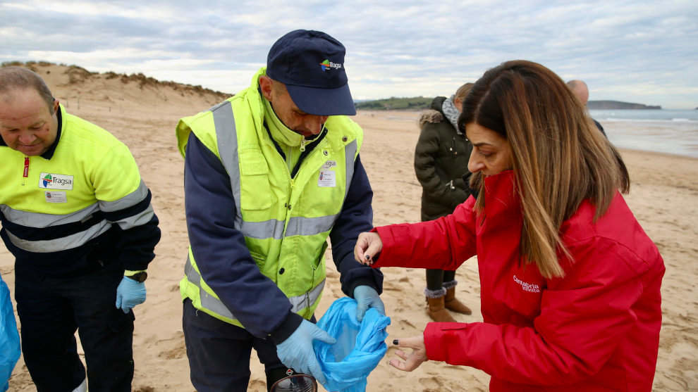 La presidenta de Cantabria, María José de Buruaga, se une a las labores de vigilancia y retirada de pélets de los operarios en la playa de Valdearenas.
