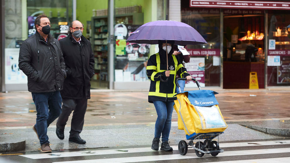 Varias personas con paraguas cruzan un paso para peatones, a 25 de noviembre de 2021, en Santander