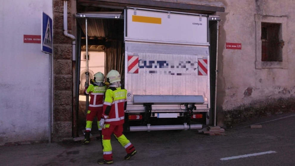 Bomberos actúan en un portón caído sobre un camión de reparto en Cóbreces