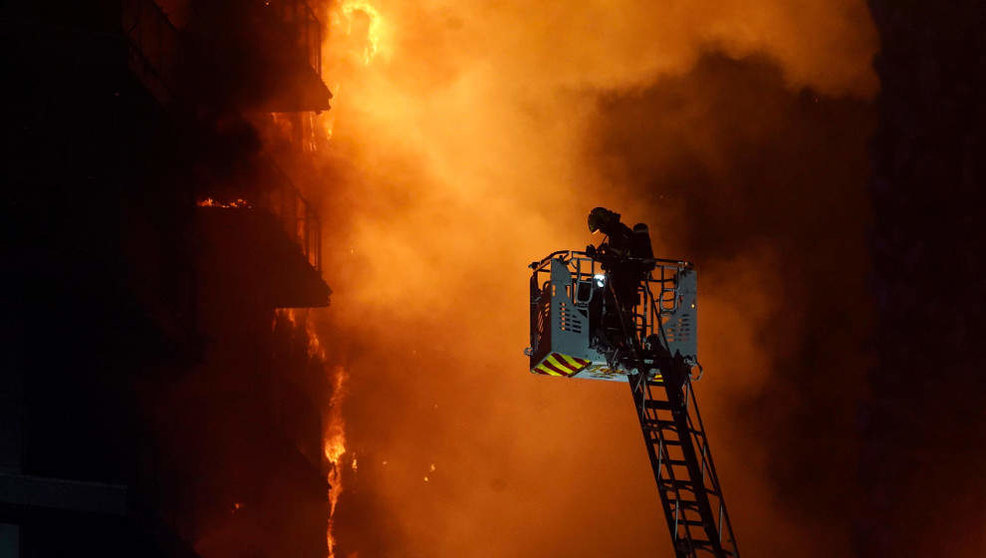 Un bombero trata de apagar el edificio en llamas, en el barrio de Campanar,
