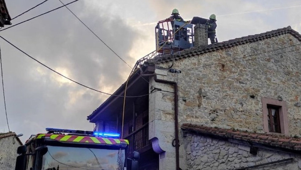 Bomberos del 112 junto a la chimenea incendiada de la vivienda