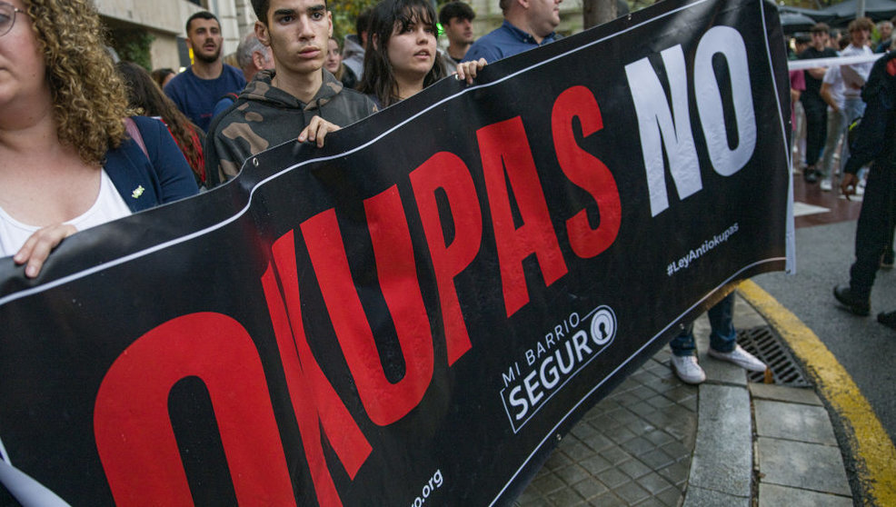 Varias personas sujetan un cartel que reza 'Okupas no' durante una protesta